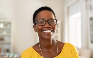 woman with large eye glasses shows off the happy, healthy smile